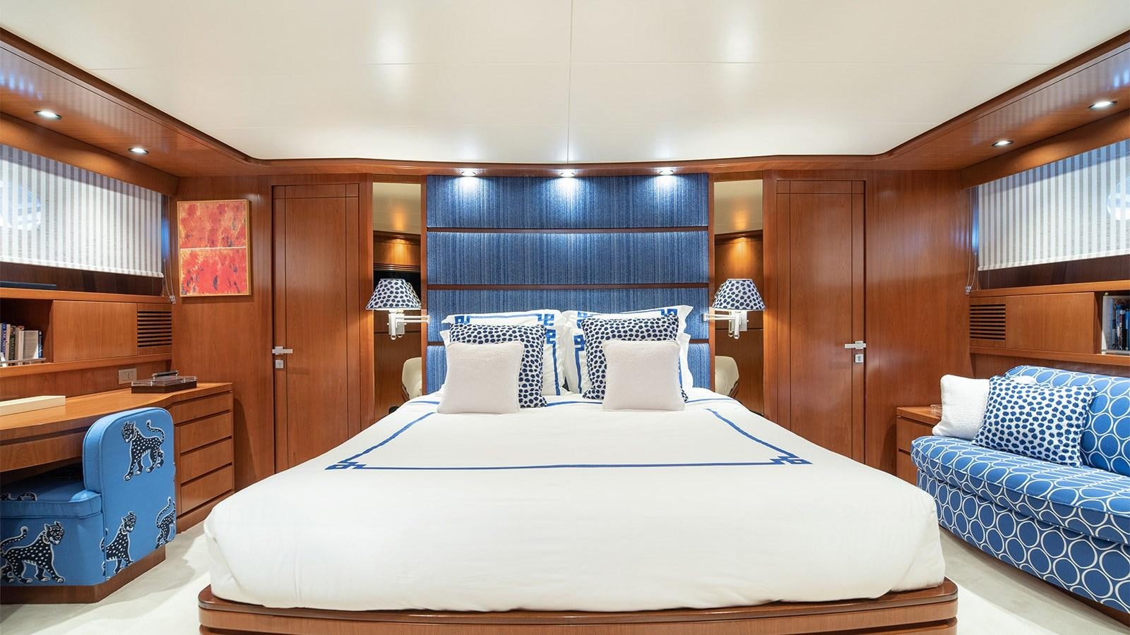 a bed with a white sheet and pillows in a room with wood cabinets aboard DIAMARE Yacht for Sale