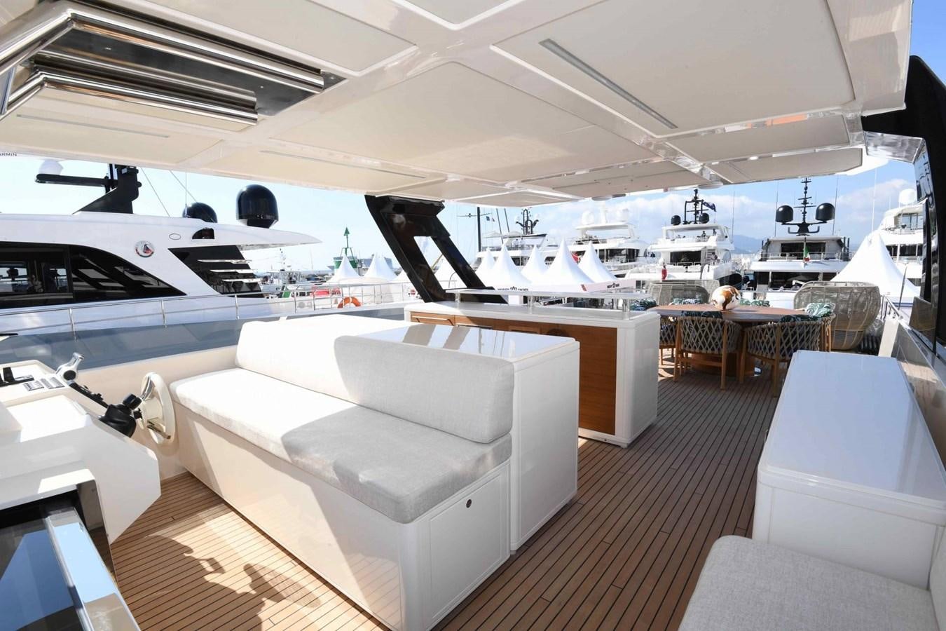 a room with a white couch and white chairs and a white table with black chairs and a large aboard CECILOU Yacht for Sale
