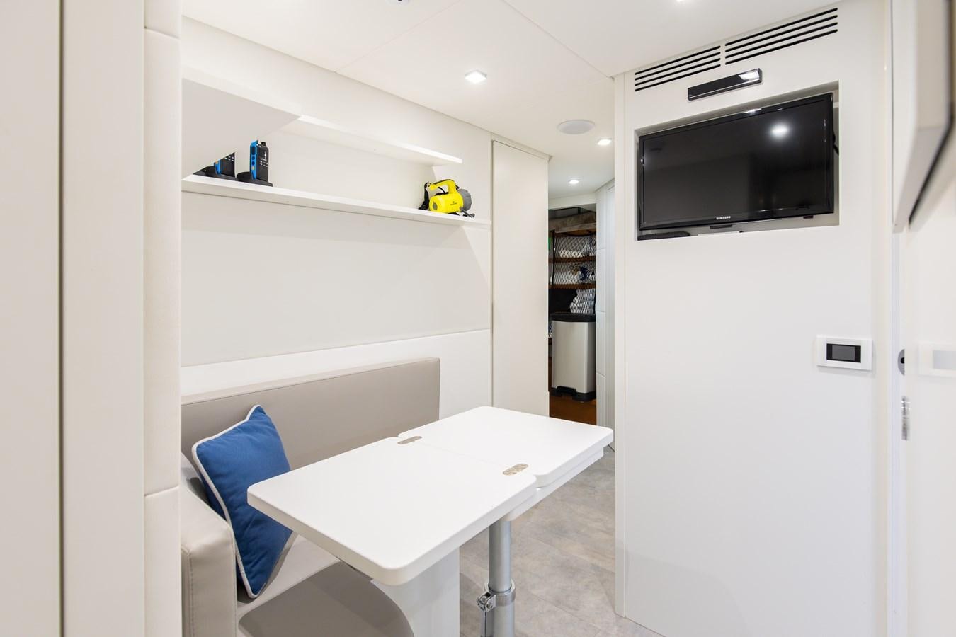 a white table with a white table and a white wall with a tv on it aboard #15 Yacht for Sale