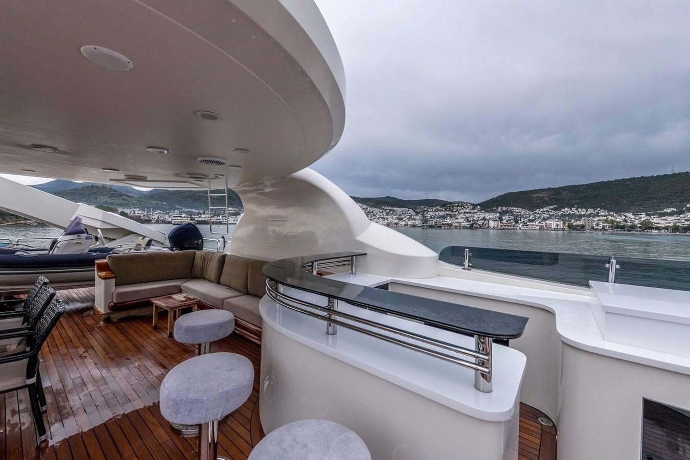 a deck with a large pool and a large city in the background aboard SERENITY II Yacht for Sale