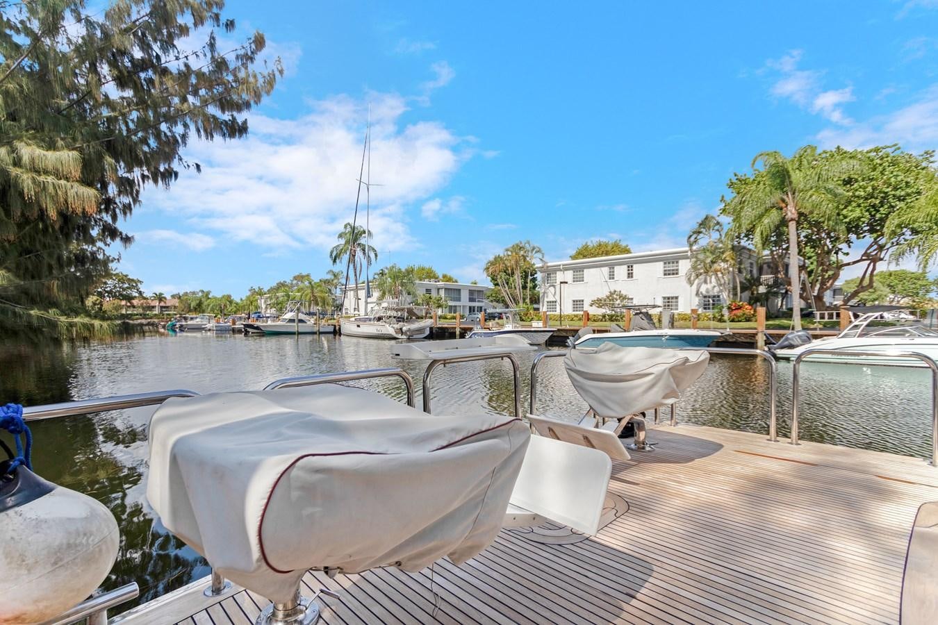 a deck with chairs and a body of water with trees and buildings in the background aboard MAC Yacht for Sale