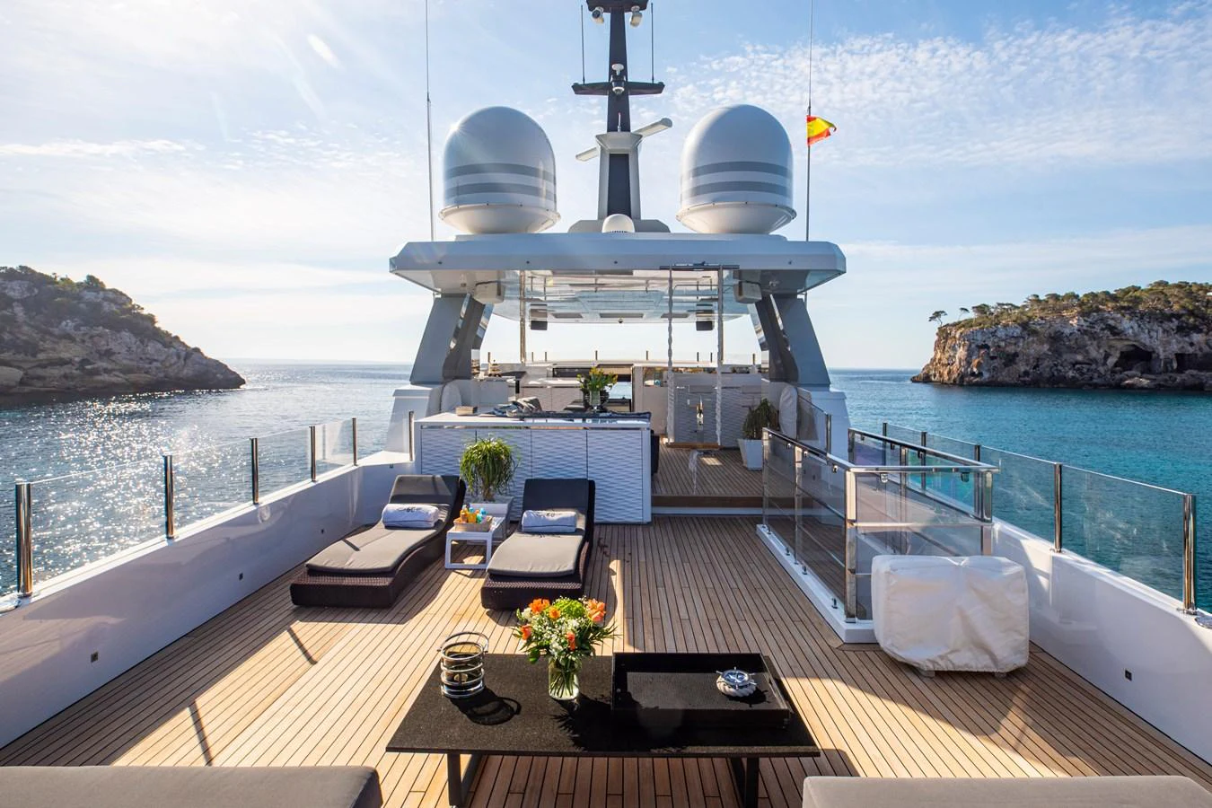 a deck with a table and chairs on it and a large ship in the background aboard CINQUANTA-50 Yacht for Charter