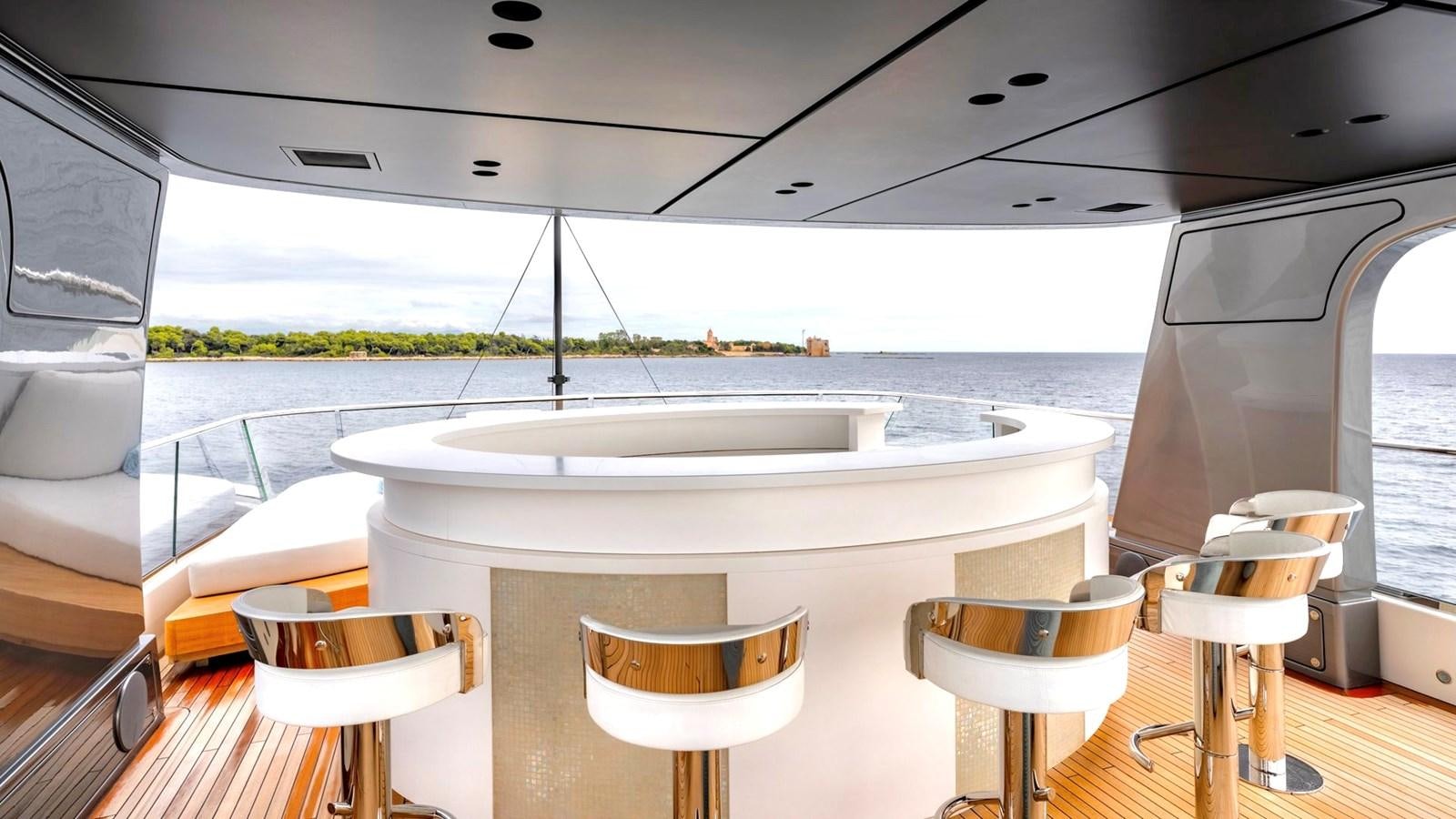 a large white table with stools next to it aboard INS LAND Yacht for Sale