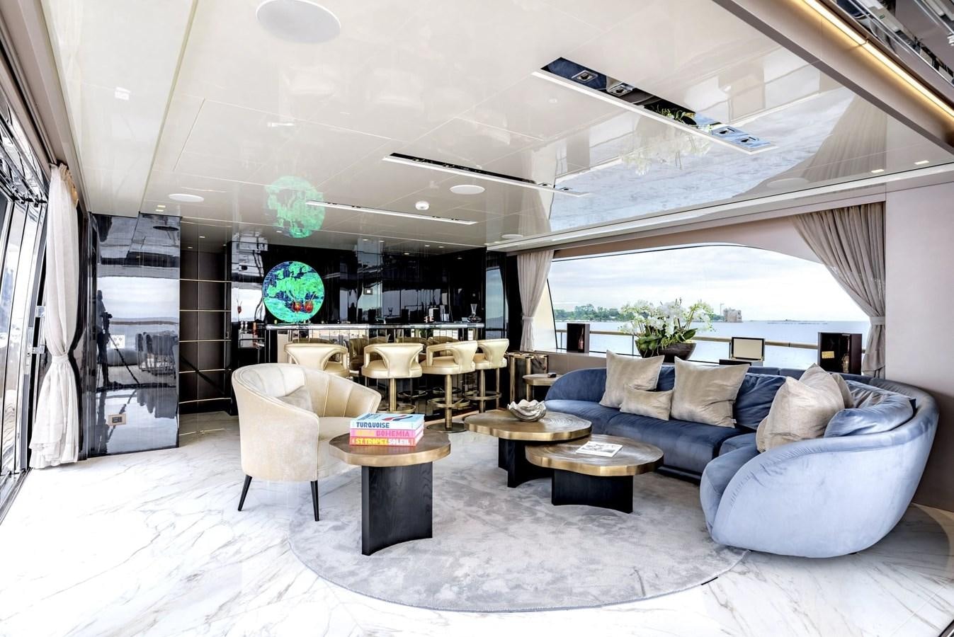 a living room with a large blue couch and a large window aboard INS LAND Yacht for Sale