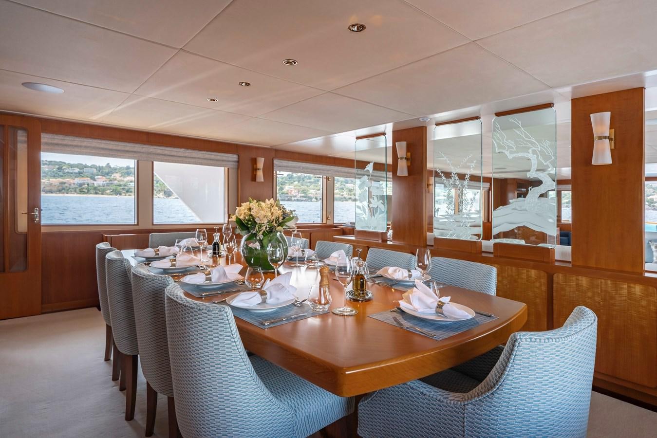 a dining table with chairs and a large window aboard SYNTHESIS 66 Yacht for Sale