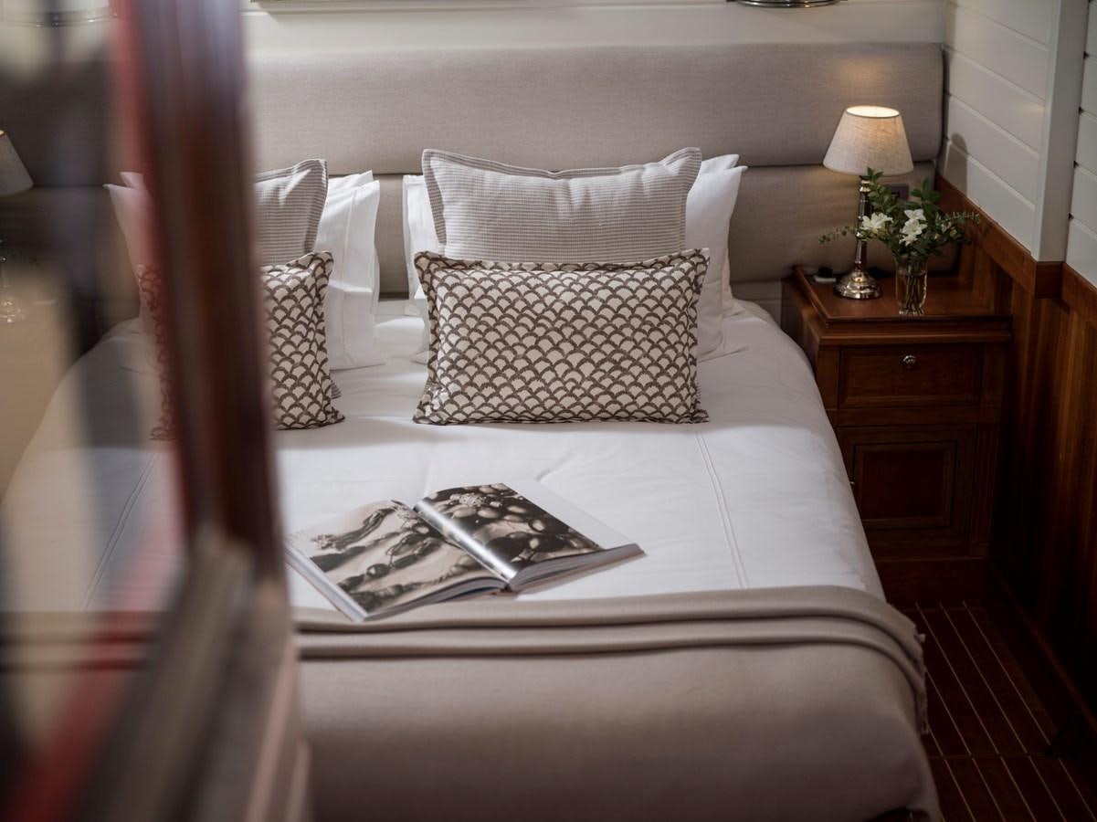 a bed with pillows and a book aboard ALEXA OF LONDON Yacht for Sale