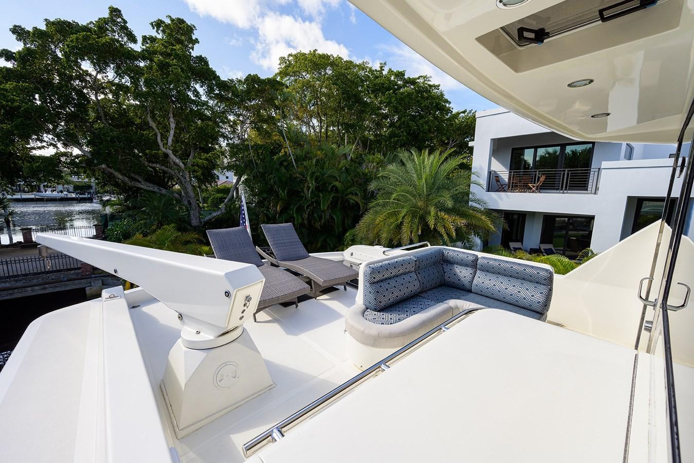 a white lounge chair on a white patio with a pool and trees aboard 82 Yacht for Sale