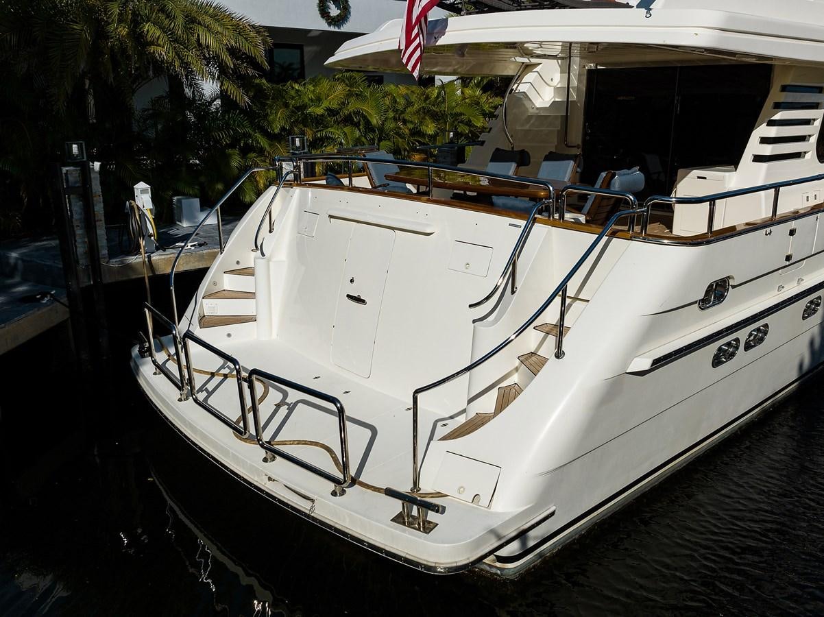 a white boat with a flag on it aboard 82 Yacht for Sale