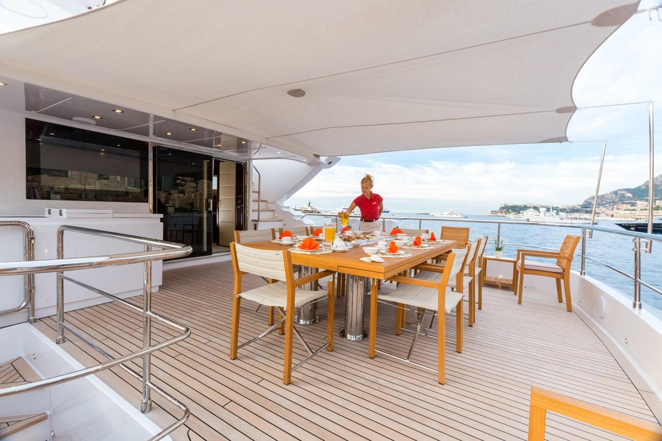 a person sitting at a table on a deck overlooking the ocean aboard GATSBY Yacht for Sale