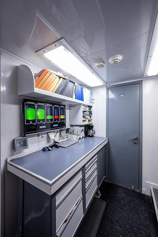 a white cubicle with a computer and a desk aboard LAGNIAPPE Yacht for Sale