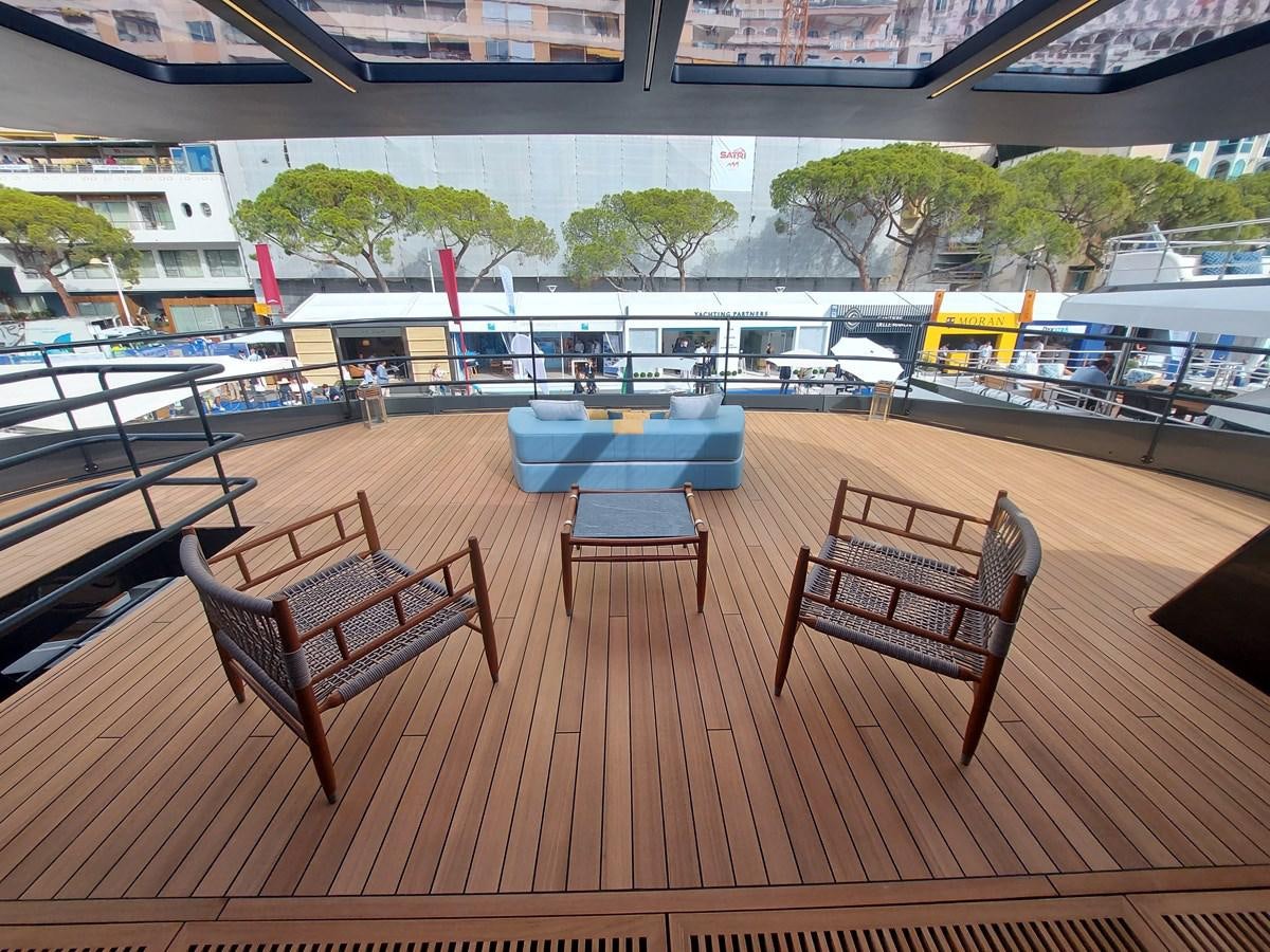 a wood deck with chairs and tables aboard M 125 Yacht for Sale