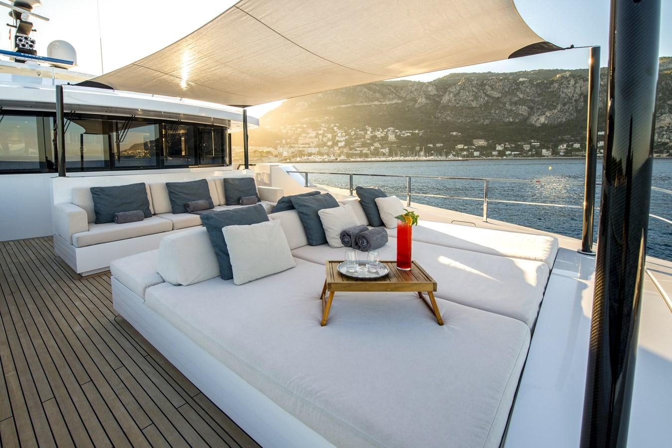 a large white bed with a white couch and a table with a red vase on it aboard AXIOS Yacht for Sale