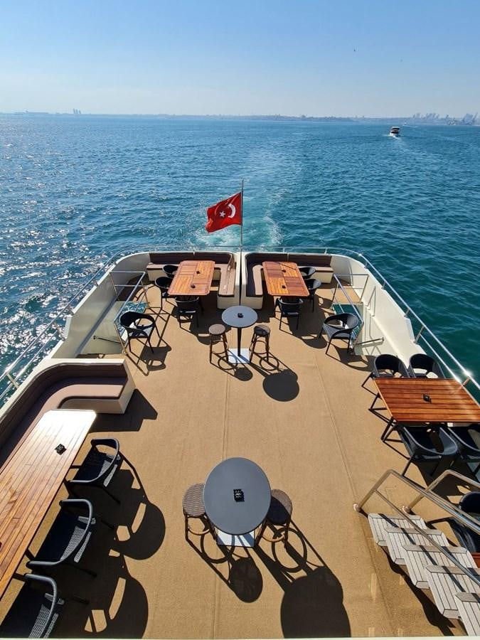 a deck with chairs and tables on it by the water aboard SINAN BEY Yacht for Sale