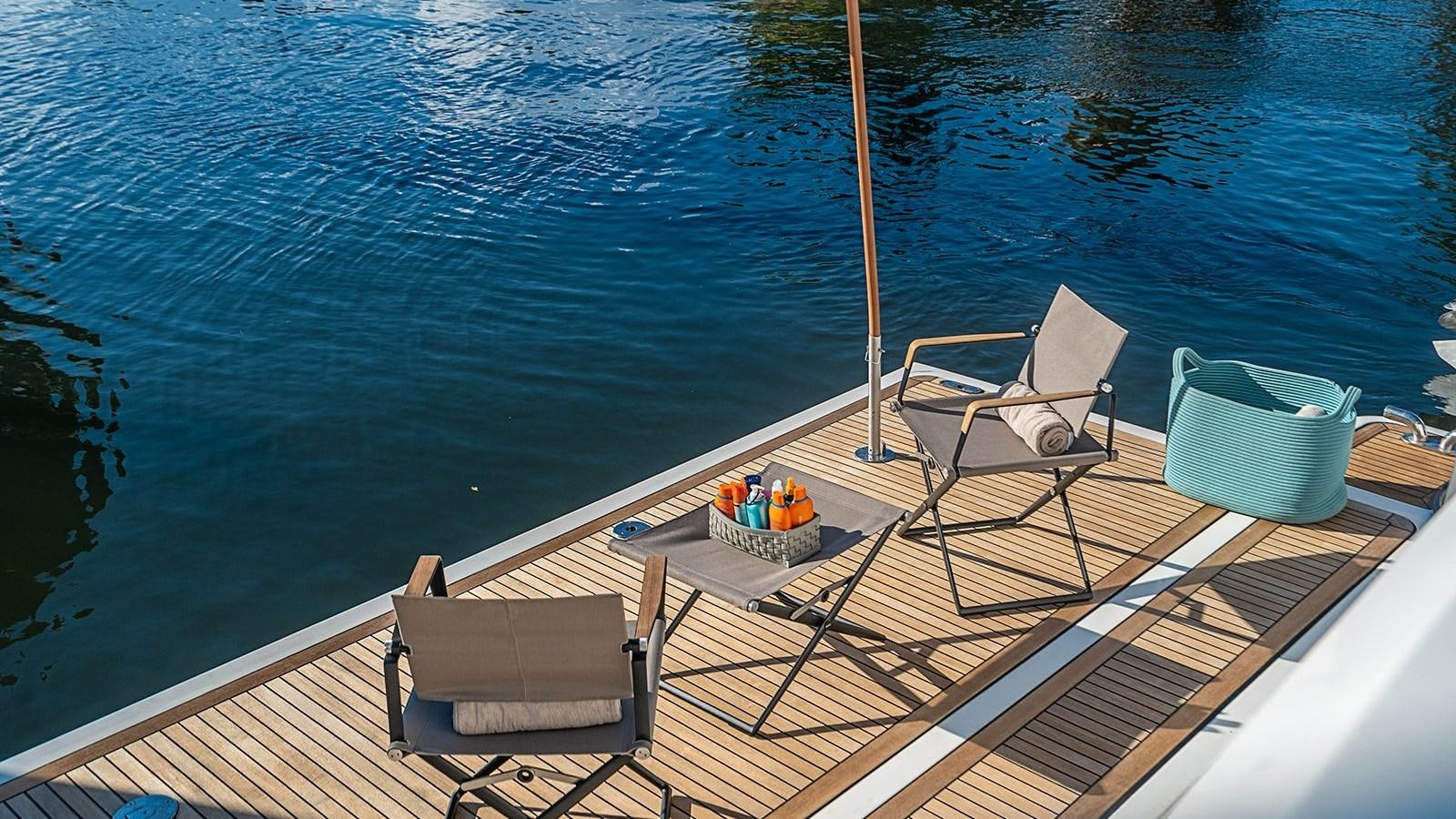 a deck with chairs and a table on it aboard PATRON Yacht for Sale