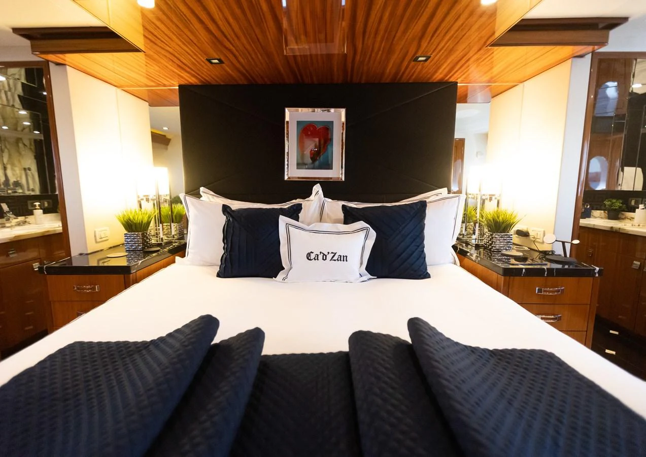 a bed with blue and white pillows aboard CA'D'ZAN Yacht for Sale