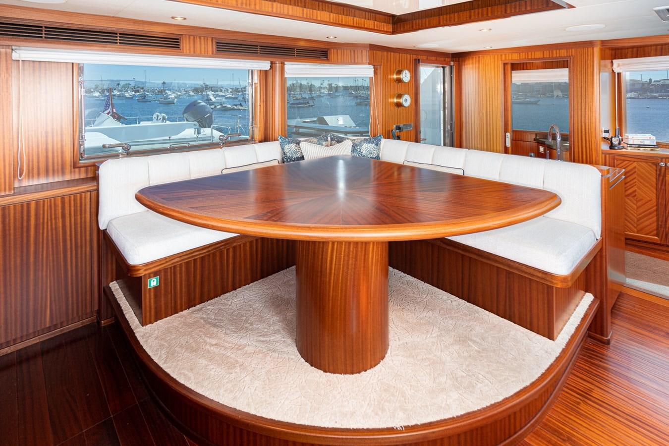 a table with a couch and a bench in a room aboard PHANTOM Yacht for Sale