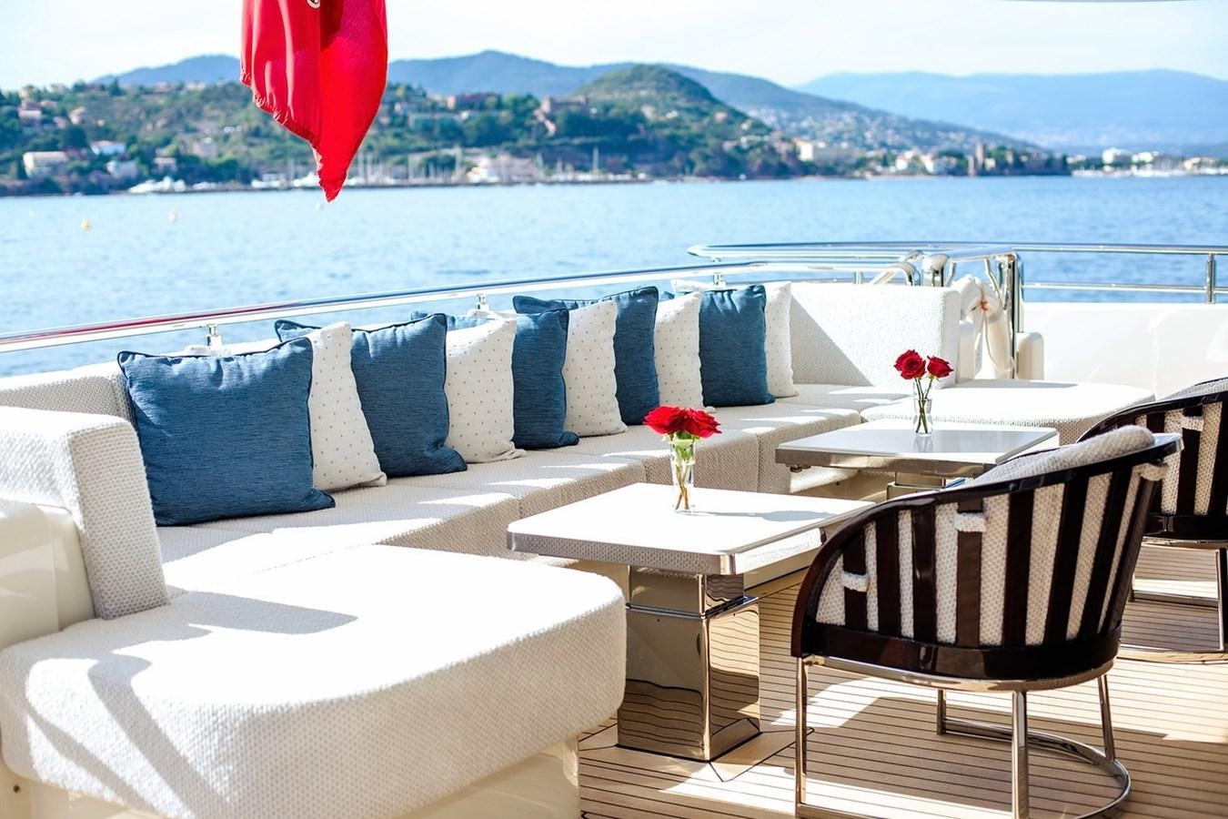 a table and chairs on a balcony overlooking a city aboard RUYA Yacht for Sale