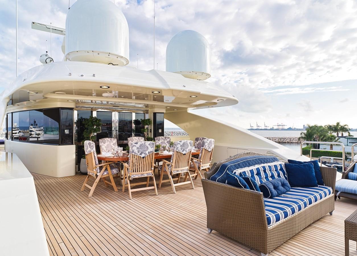 a large patio with a couch and chairs and a large white building with a view of the ocean aboard BLUE EYES LONDON Yacht for Sale