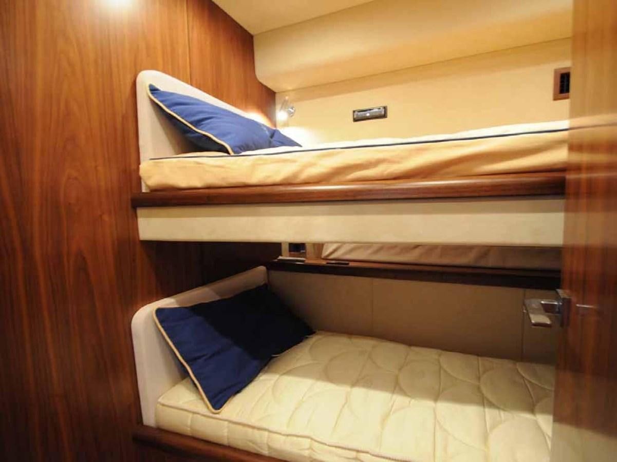 a bed with a white sheet and blue and white pillows aboard JUNIOR Yacht for Sale