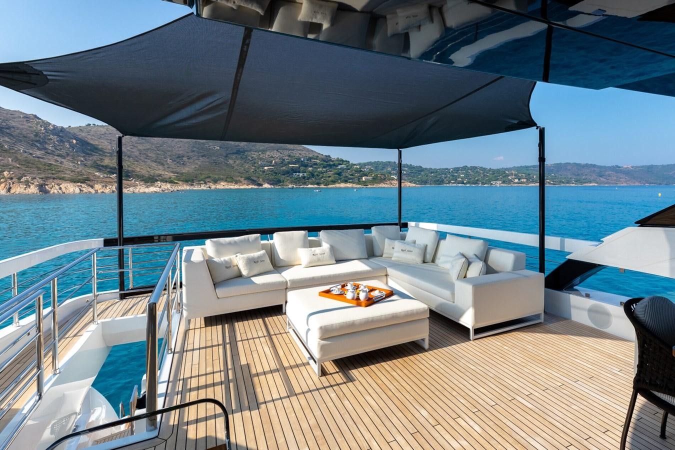 a large lounge area with a large body of water and mountains in the background aboard RAPH SEVEN II Yacht for Sale