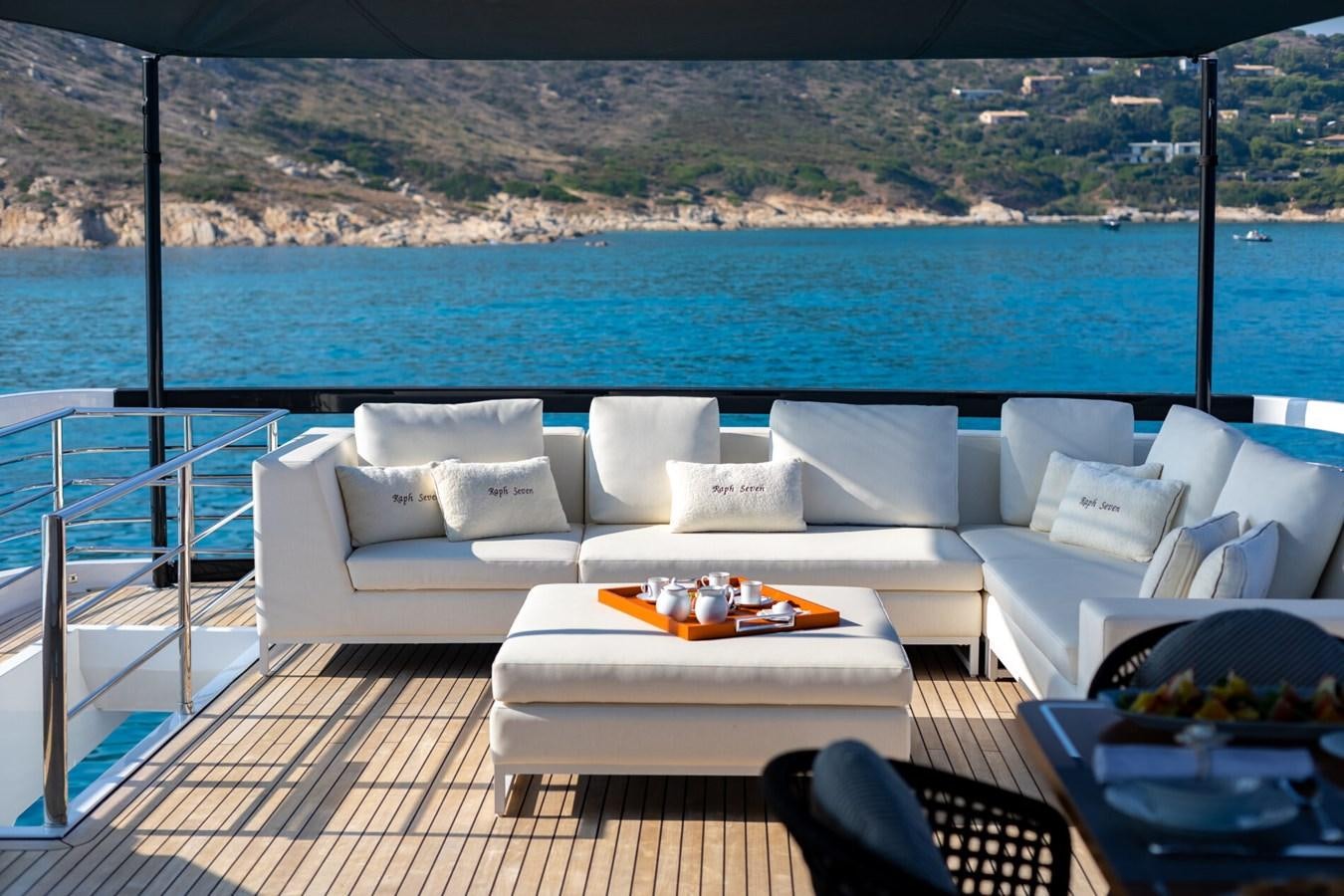 a large white couch on a deck overlooking a large body of water aboard RAPH SEVEN II Yacht for Sale
