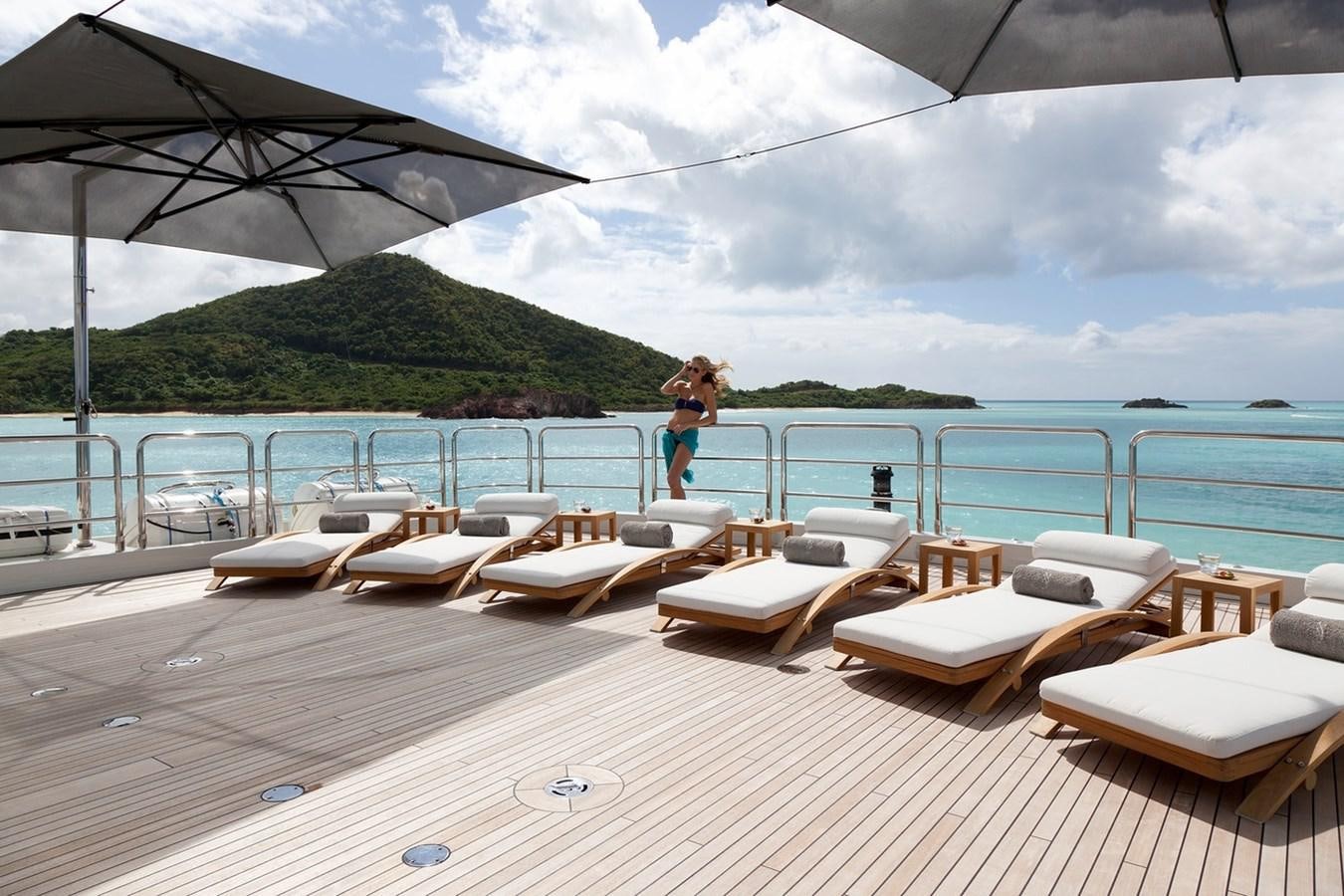 a person standing on a deck with chairs and a large body of water in the background aboard SEANNA Yacht for Sale