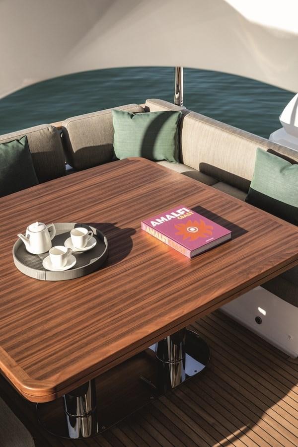 a table with a book and a cup on it aboard 2023 MAGELLANO 66 Yacht for Sale