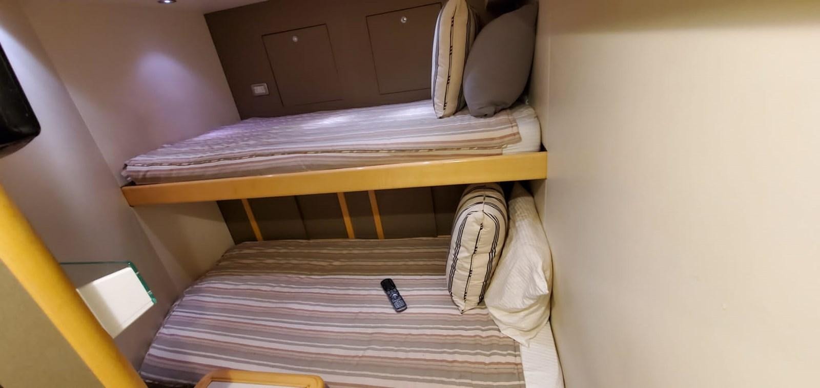 a bunk bed with a purple striped blanket and a white shoe on it aboard RUMBERA Yacht for Sale