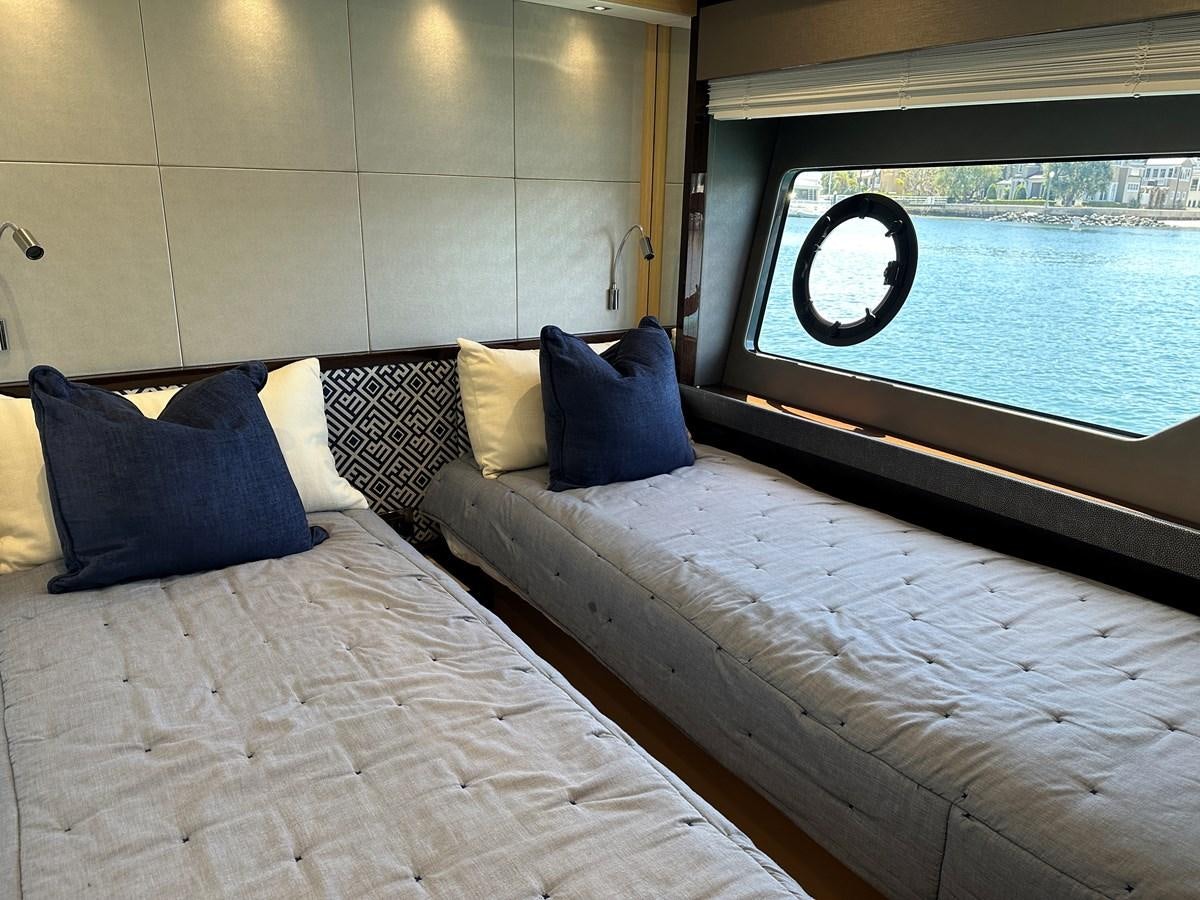 a bed with a blue pillow and a window with a view of a city aboard K NUK Yacht for Sale