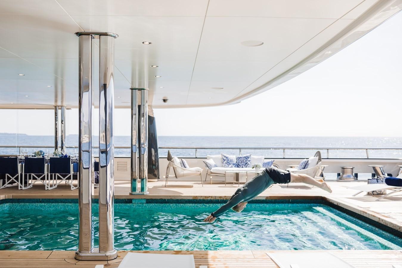 a person lying on a lounge chair in a swimming pool aboard HERE COMES THE SUN Yacht for Sale