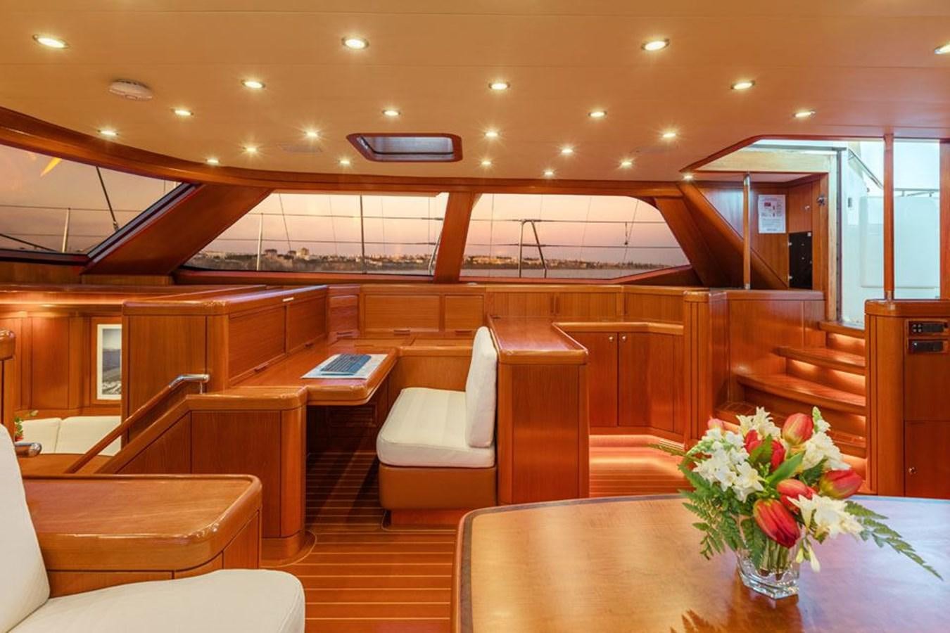a room with a table chairs and a vase with flowers in it aboard PAULINE AF SKANOR Yacht for Sale