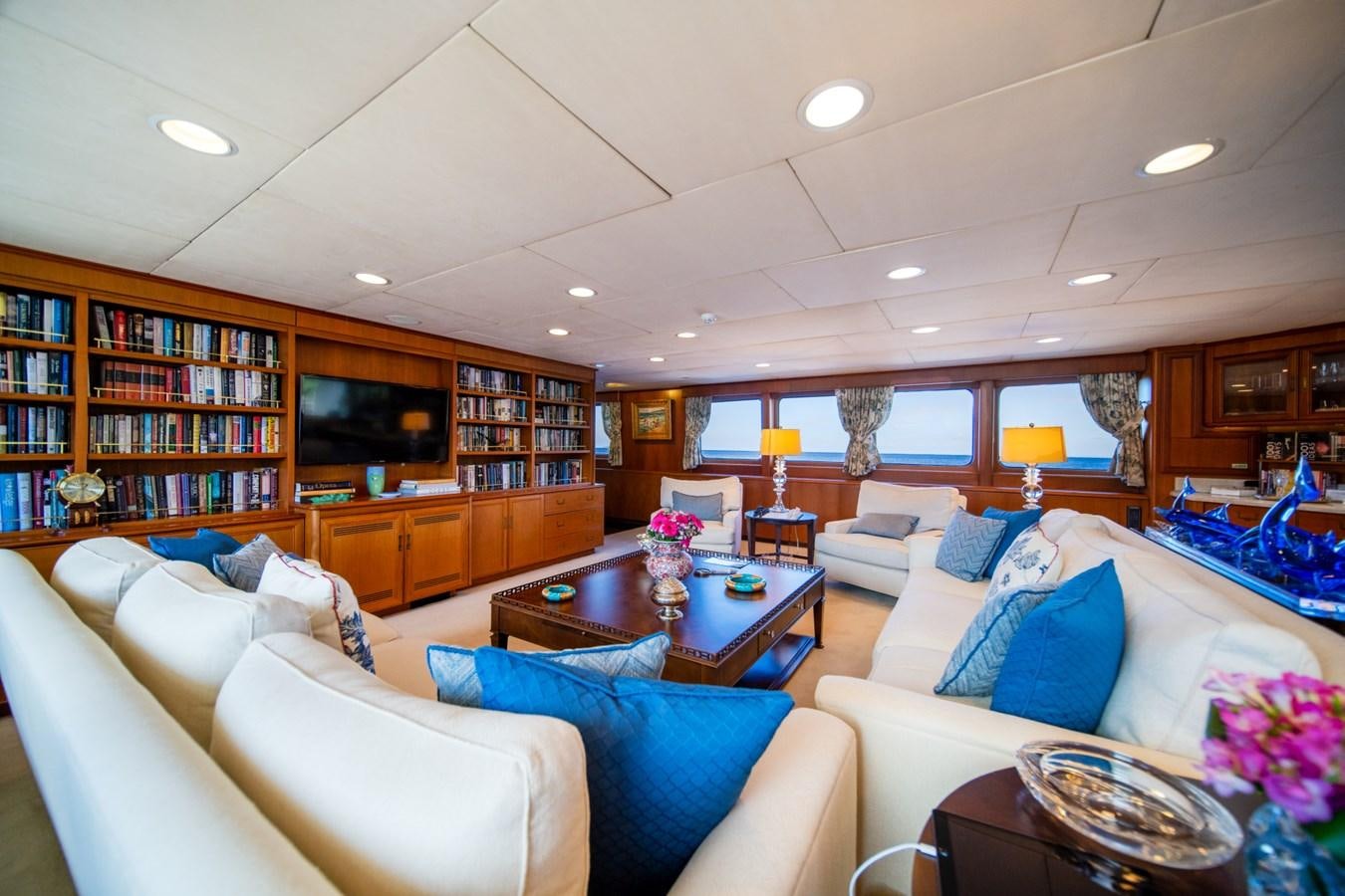 a living room with a large book shelf and a table aboard SEA FALCON II Yacht for Sale
