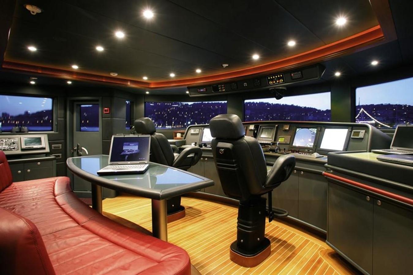 a person sitting at a table in a room with a laptop and a tv on the wall aboard SEASCAPE V Yacht for Sale