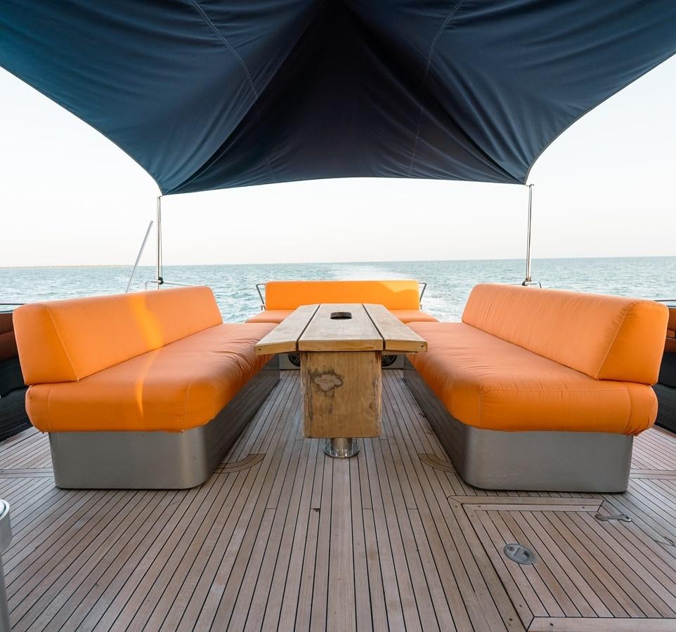 a group of orange couches with a black umbrella over them aboard SCRATCH Yacht for Sale