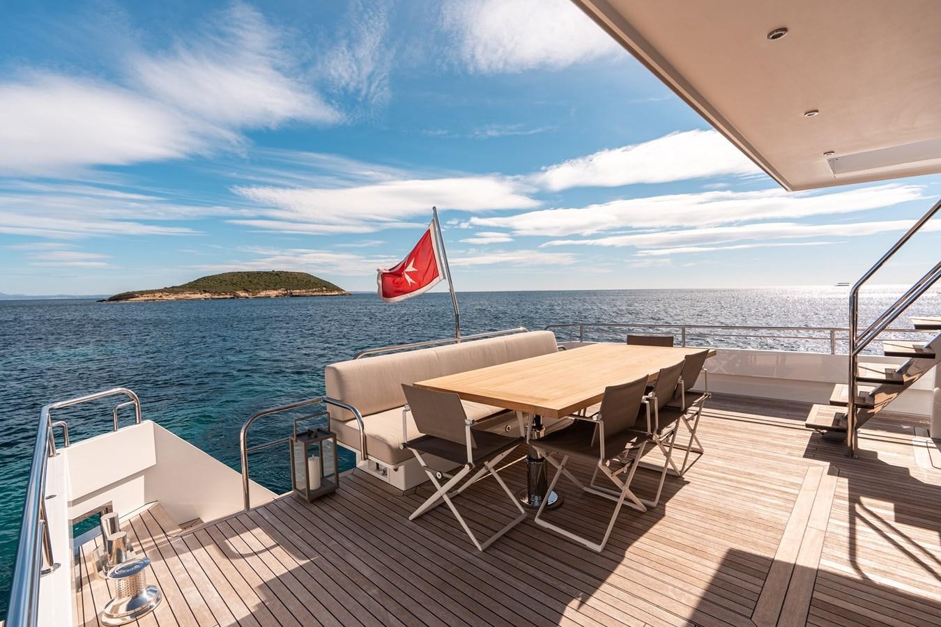 a table and chairs on a deck overlooking the ocean aboard SHOCKWAVE Yacht for Sale
