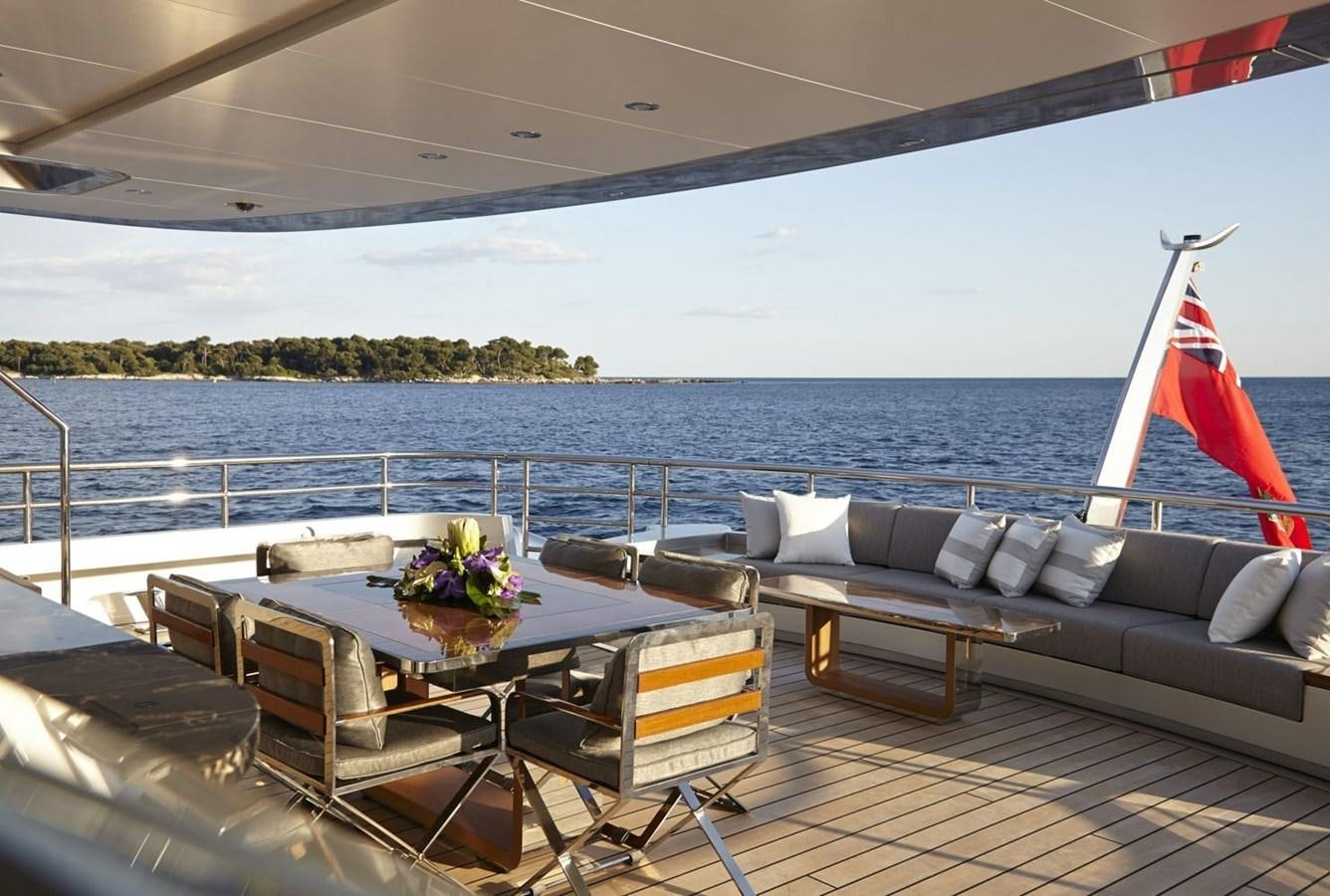 a table and chairs on a deck overlooking a body of water aboard EXCELLENCE V Yacht for Sale