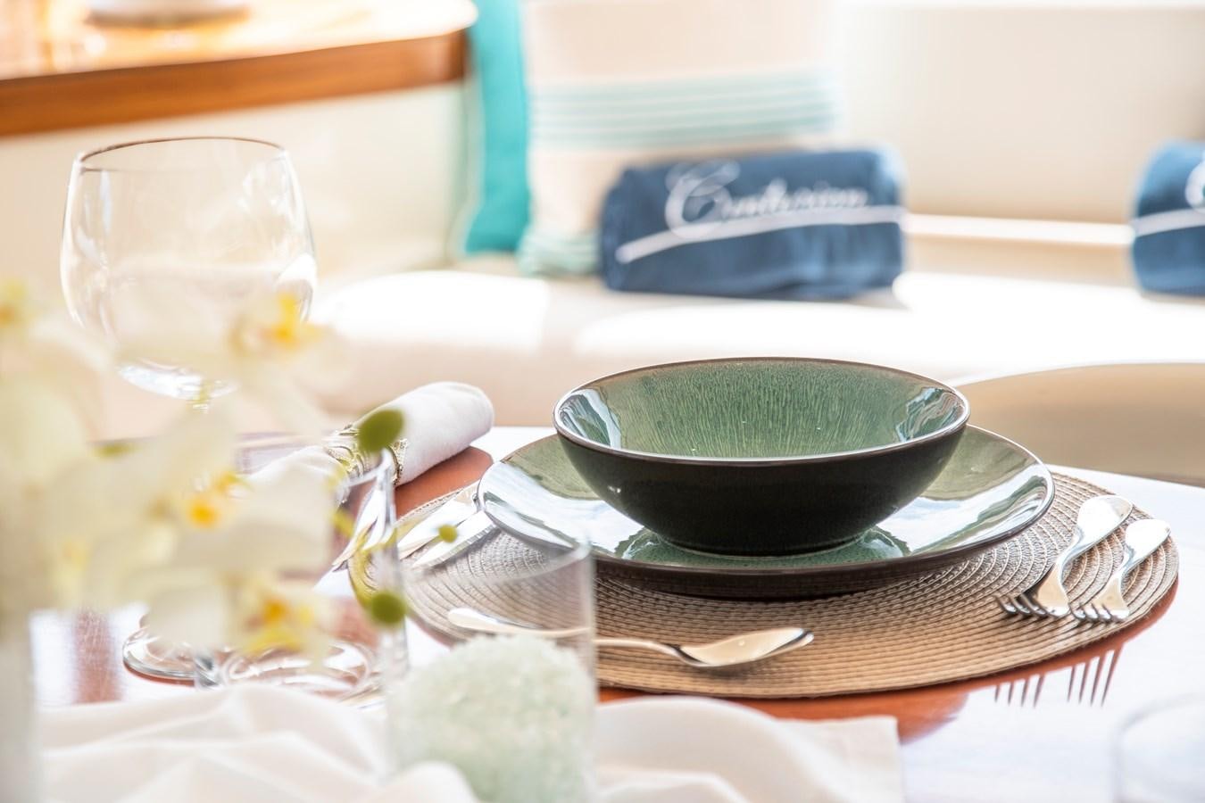 a bowl of green soup on a plate with a napkin and a plate of food aboard CENTURION Yacht for Sale