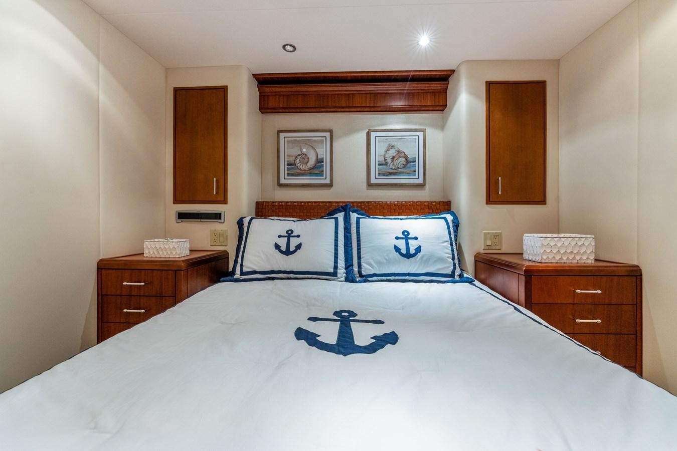 a bed with a white sheet and blue and white pillows aboard RUMOURS Yacht for Sale