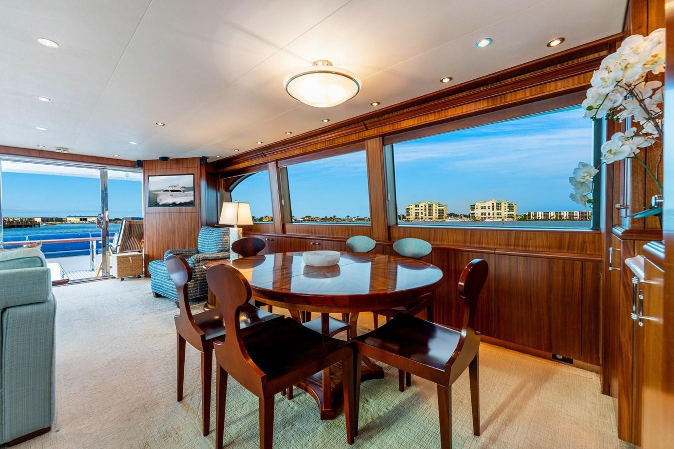 a dining table and chairs in a room with a view of the city aboard RUMOURS Yacht for Sale