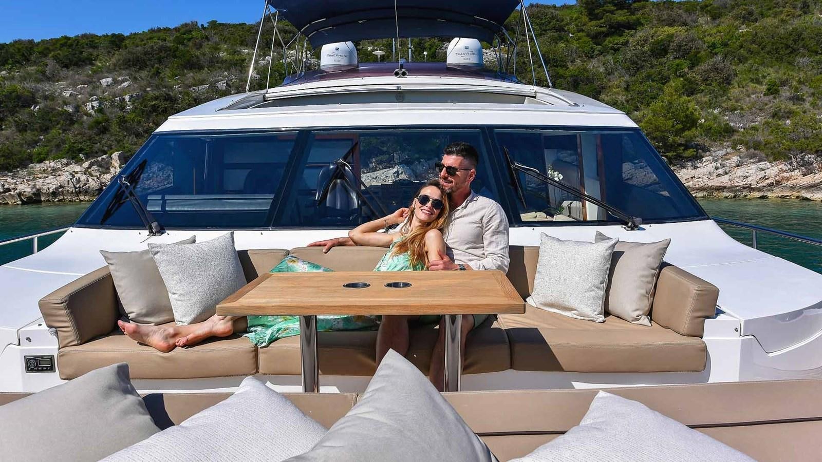 a man and woman sitting at a table in front of a boat aboard AGAVE Yacht for Sale