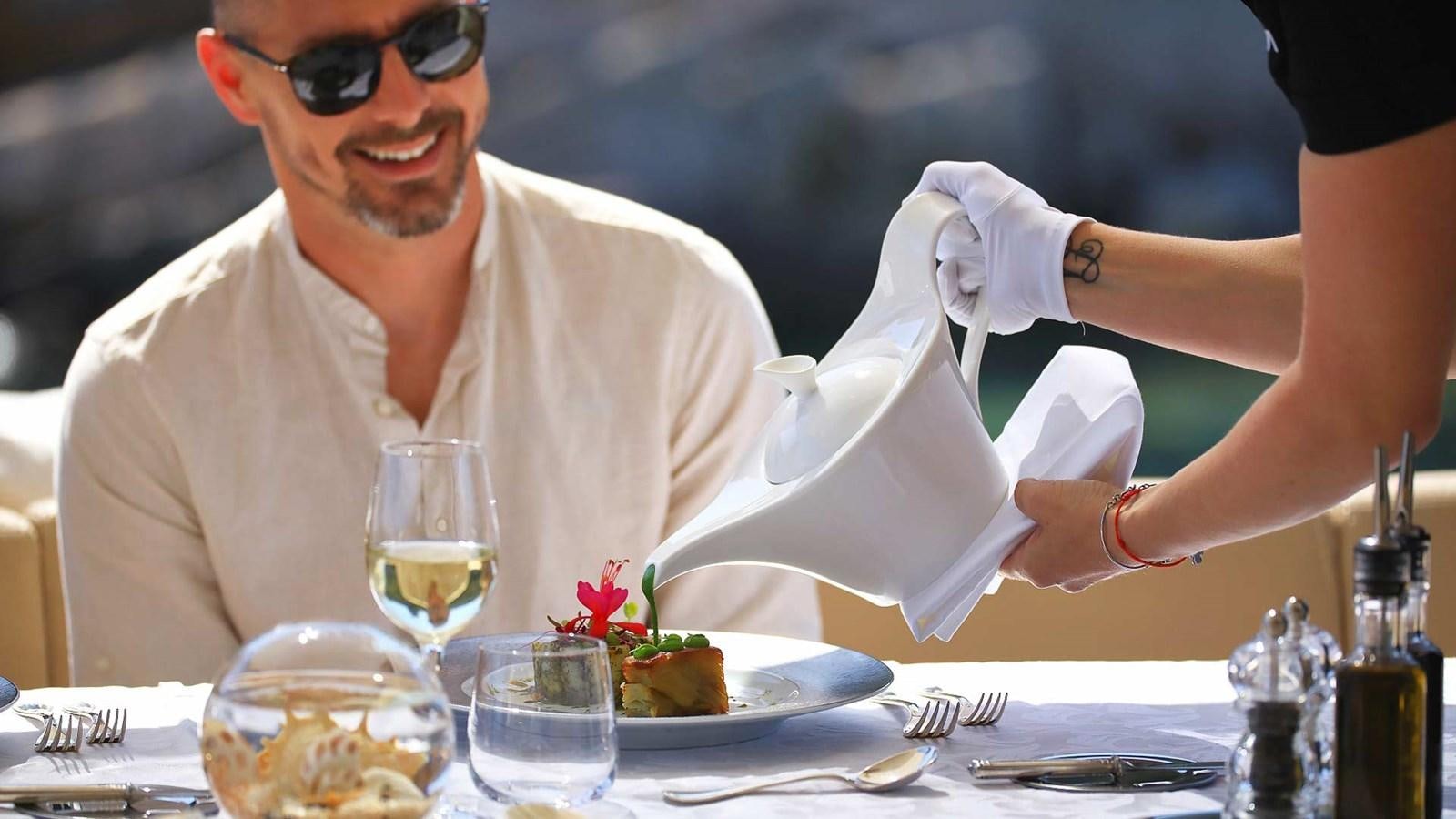 a person pouring wine into a glass aboard AGAVE Yacht for Sale