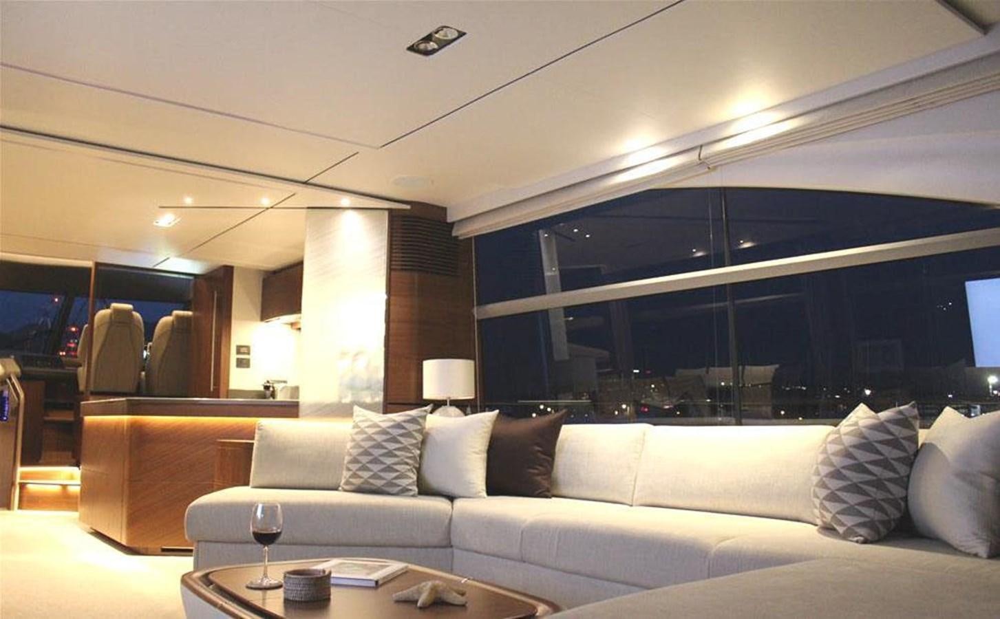 a white couch with pillows and a coffee table in a room with a large window aboard XM Yacht for Sale