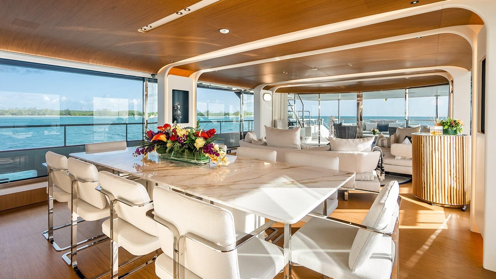 a large white dining table in a room with white chairs and a large window with a view of aboard KOJU Yacht for Sale
