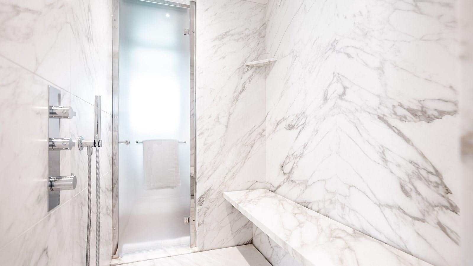 a white bathroom with a shower curtain aboard KOJU Yacht for Sale