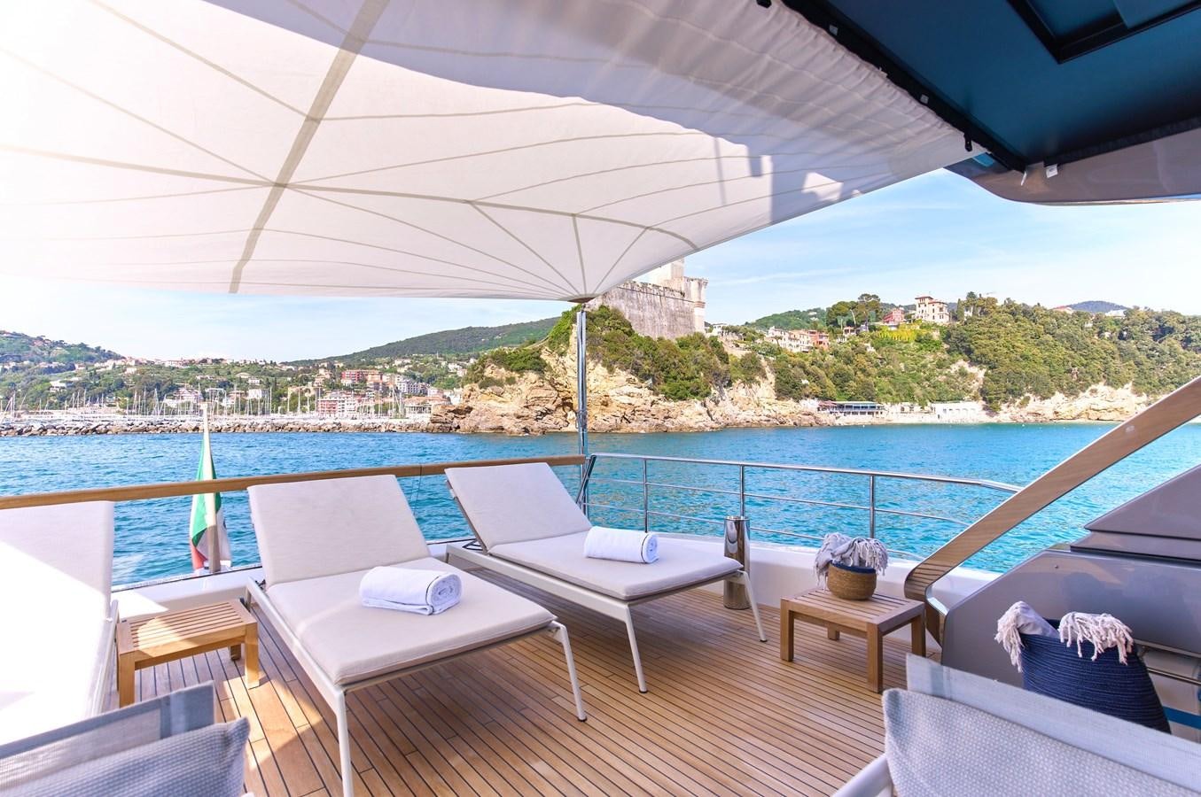 a deck with chairs and a body of water and trees in the background aboard ESTIA Yacht for Sale