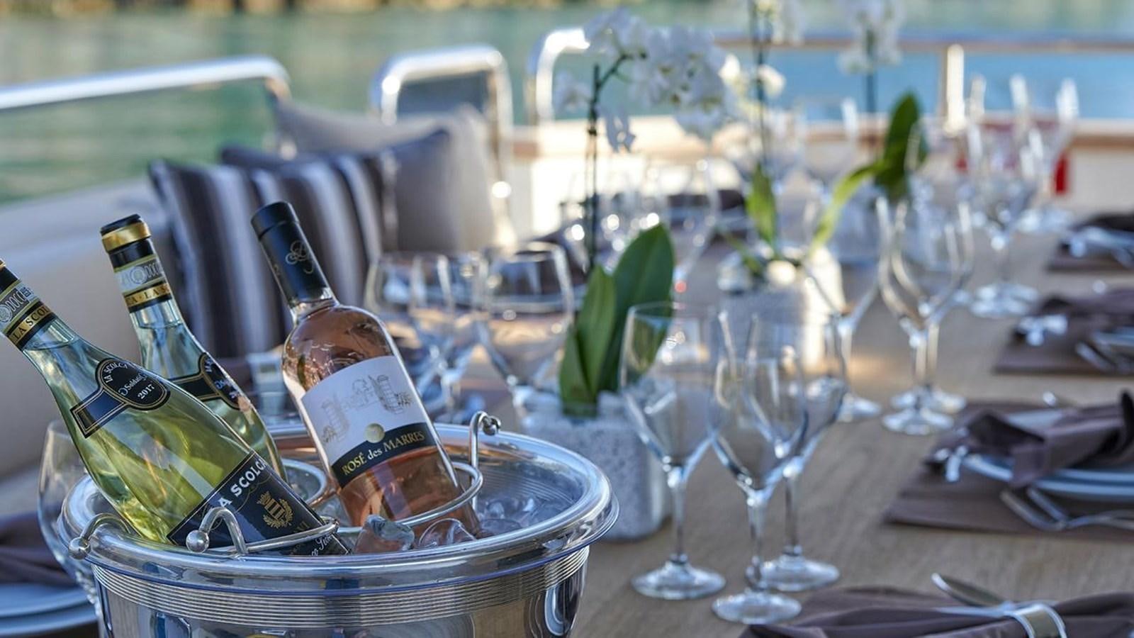 a bottle of wine and glasses on a table aboard SANSARA Yacht for Sale