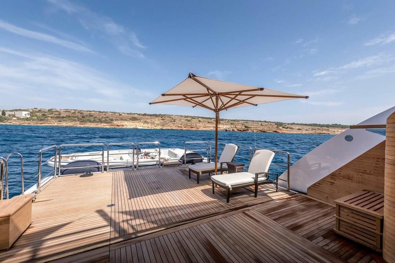 a deck with chairs and umbrellas on it by the water aboard TALISMAN C Yacht for Sale