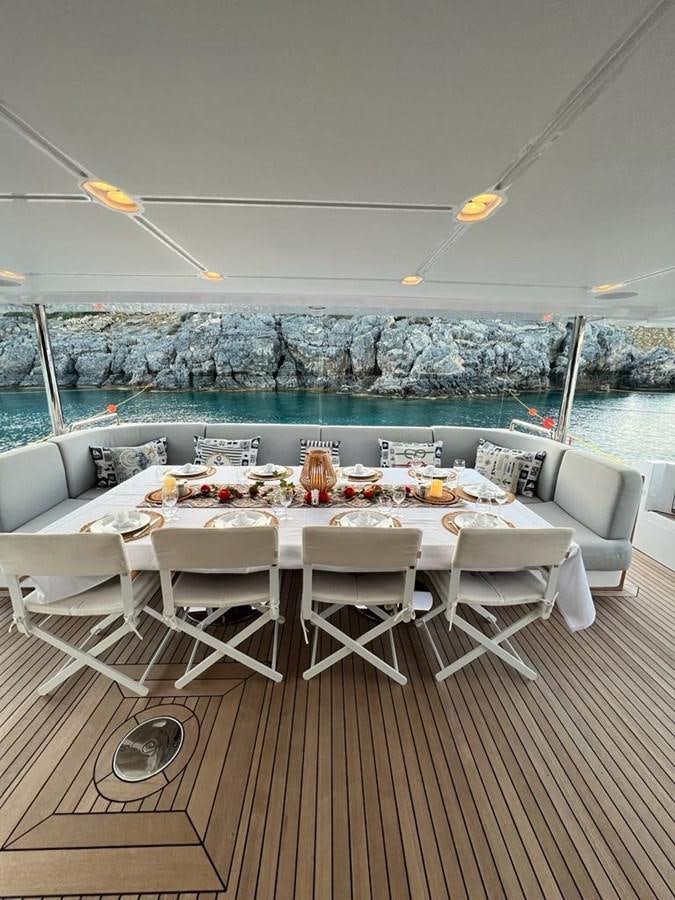 a table set for a meal on a deck overlooking a swimming pool aboard LOVE T Yacht for Sale