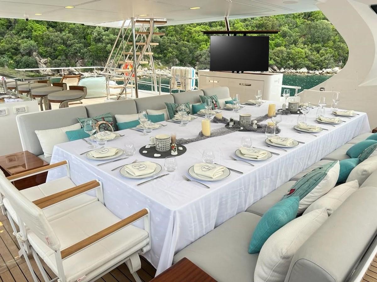 a table set with plates and chairs aboard LOVE T Yacht for Sale