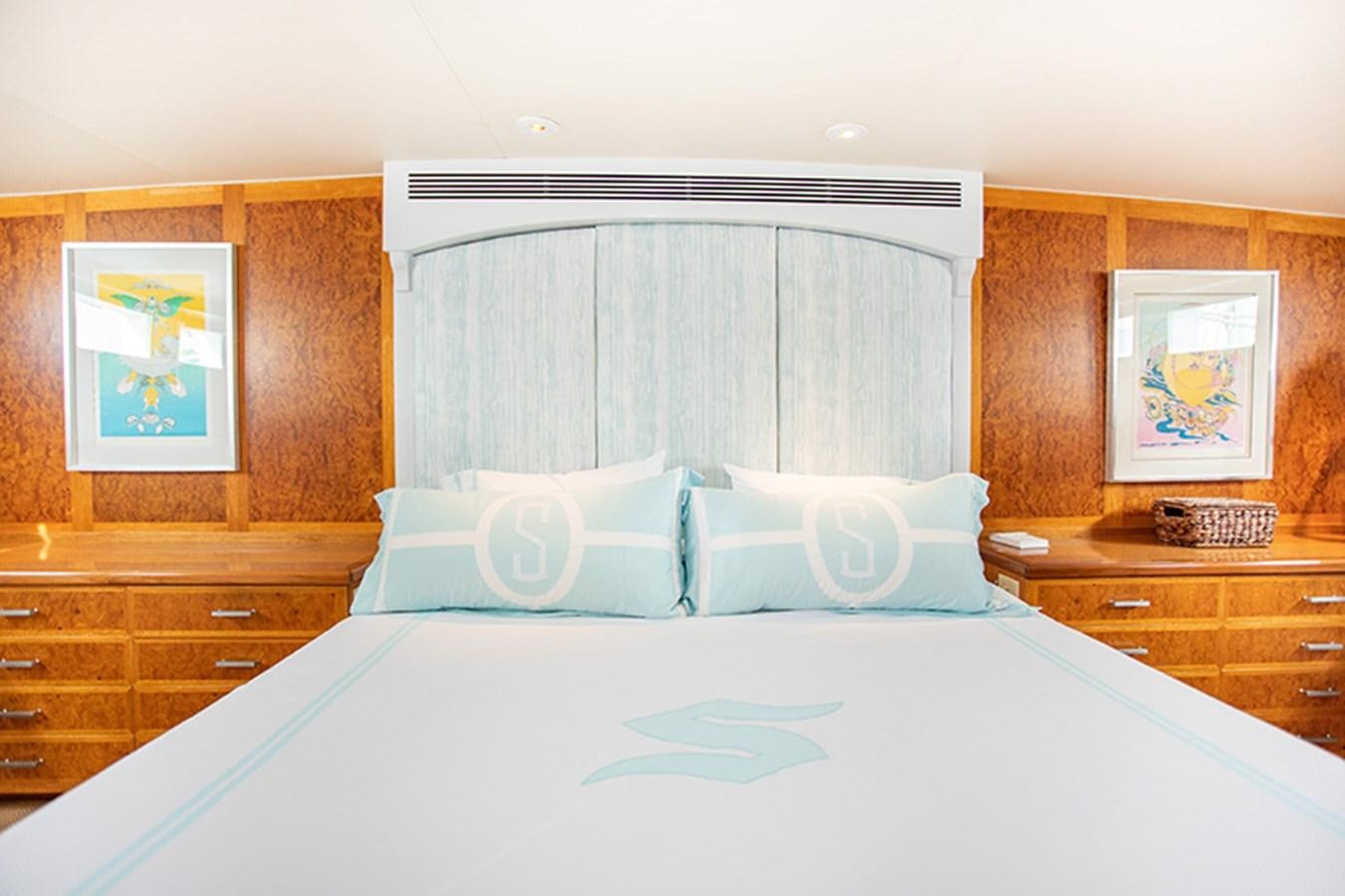 a bed with a blue and white comforter and a wooden wall aboard SOVEREIGN Yacht for Sale